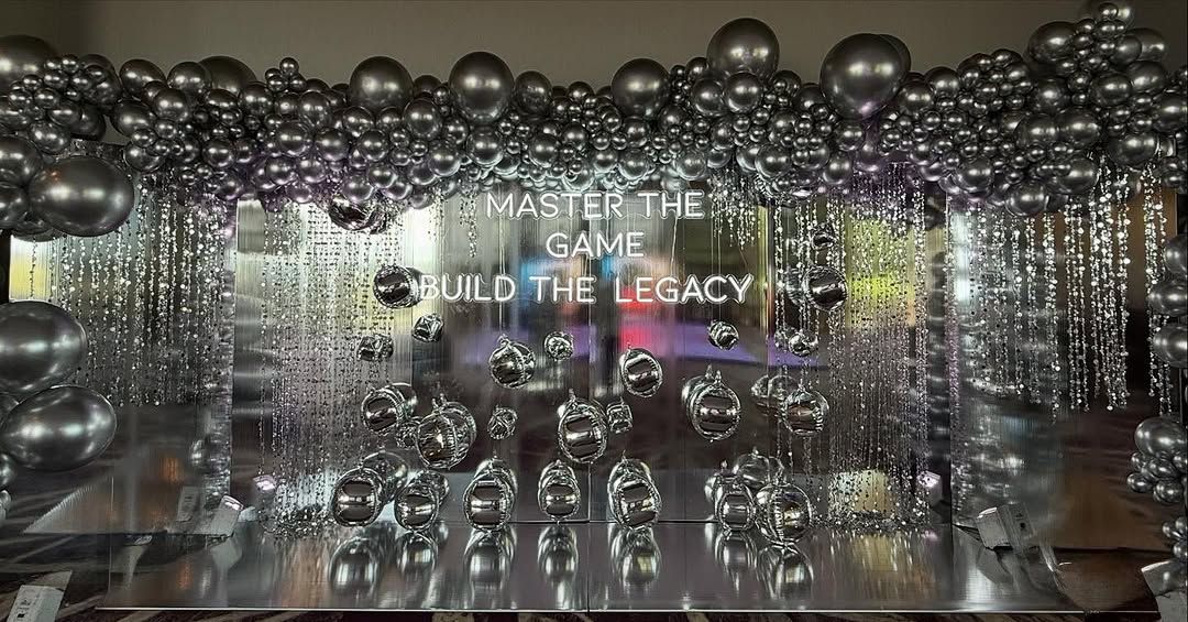Silver corporate event backdrop with Master the Game Build the Legacy text